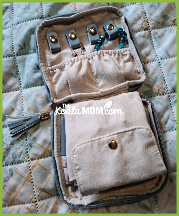 Blue travel jewelry case lays open, showing soft interior with a couple bracelets tucked into pouch. Photo by Bonnie Way.